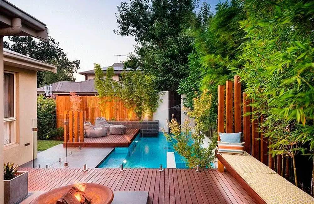 Piscina 2x6 com deck de madeira e paisagismo no entrono