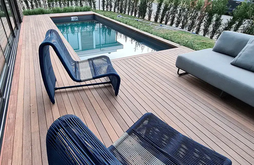 Deck com m[oveis de corda na frente da piscina