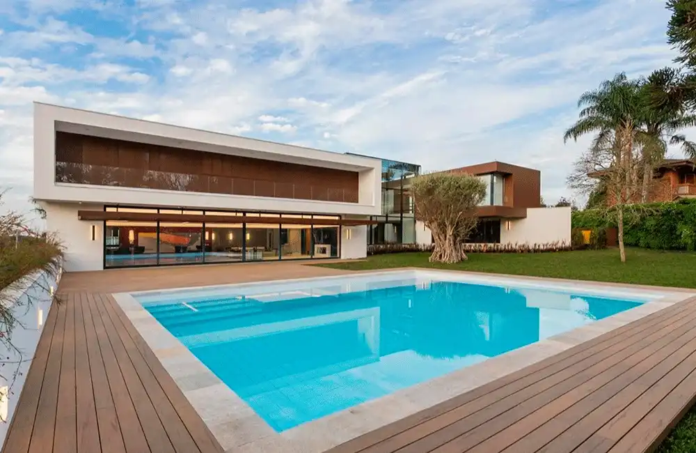 piscina com borda branca e pedras e deck ecológico em volta 