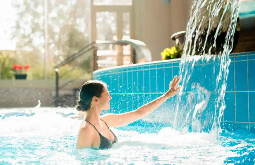 Piscina Aquecida: Vale a Pena? Benefícios e Dicas 12 mulher na piscina com cascata