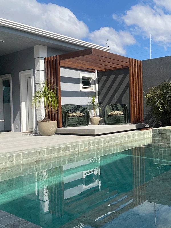 Pergolado de canto piscina com deck e balanços