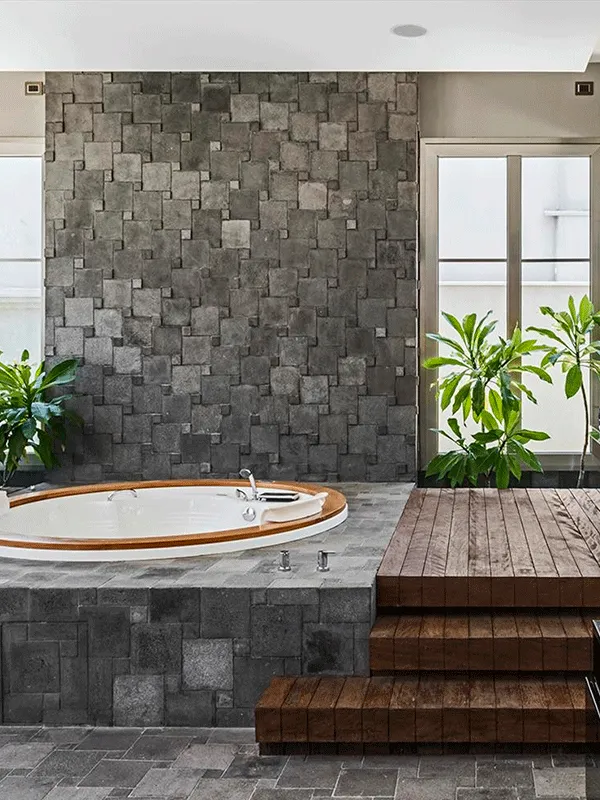 banheiro com banheira com uma parede de pedra hijau na decoração