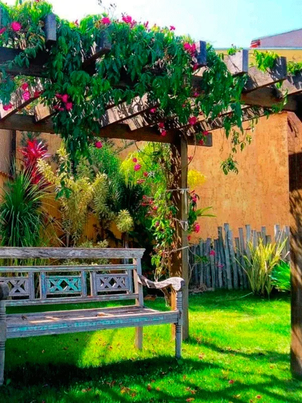 Pergolado com banco e flores coloridas no jardim