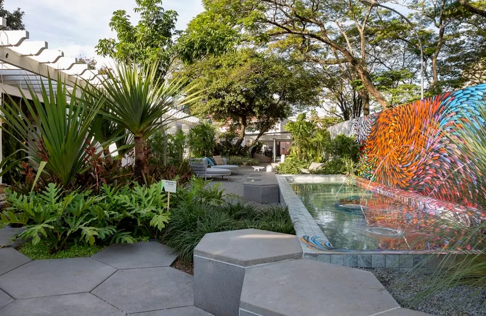 Piso para área externa em volta da piscina de alvenaria com parede pintada por artista