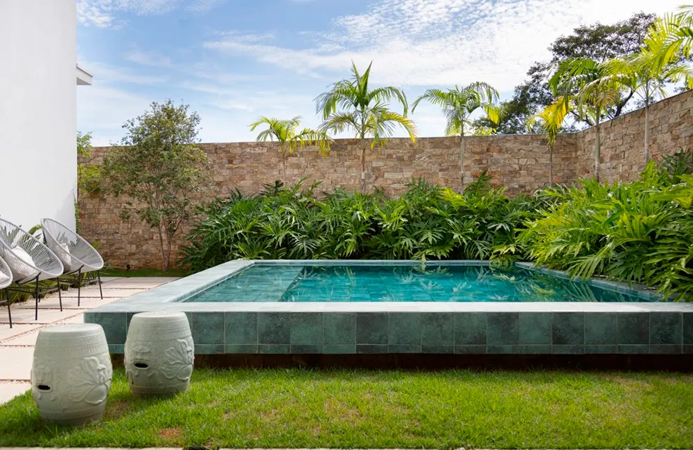 Piscina elevada no jardim com jardim vertical e pedra hijau