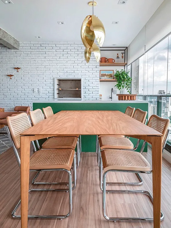 sala dejantar com mesa de madeira, churrasqueira e piso lamiando para uma decoração rústica