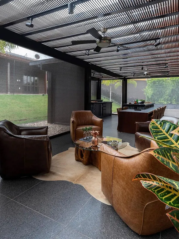 area de lazer com pergolado preto com piso de porcelanato escuro e fosco