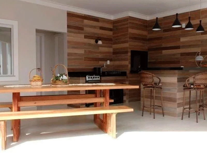 cozinha com área de churrasqueira com porcelanato amadeirado na parede 