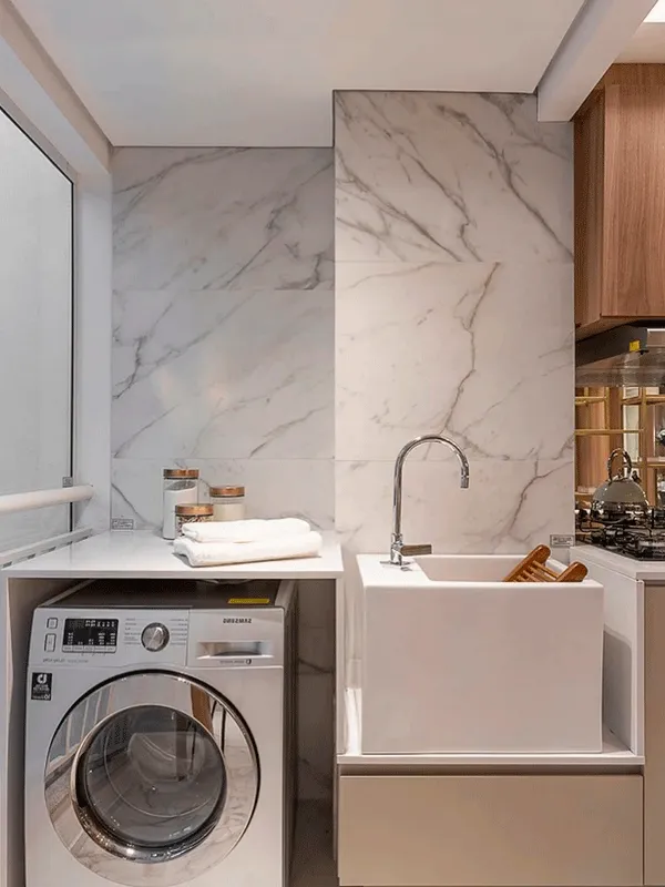 área de serviço com parede de porcelanato marmorizado com maquina de lavar em destaque