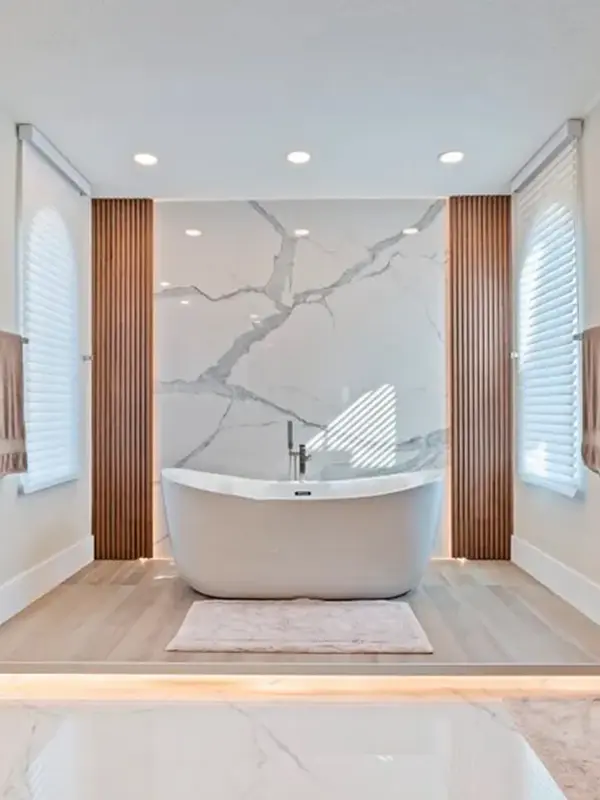 banheiro com banheira com revestimento de porcelanato calacata na parede bem decorada