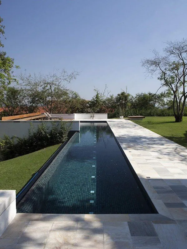 espaço grande com piscina retangular, revestimento branco em volta