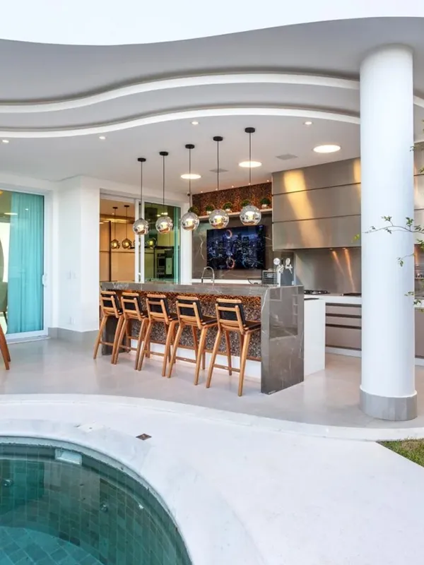 Descubra os 7 Modelos de Porcelanato para Área Gourmet: Elegância e Praticidade de Limpeza 104 cozinha moderna para área gourmet com cores brancas no piso em volta da piscina e piso de cimento queimado dentro da área de churrasqueira