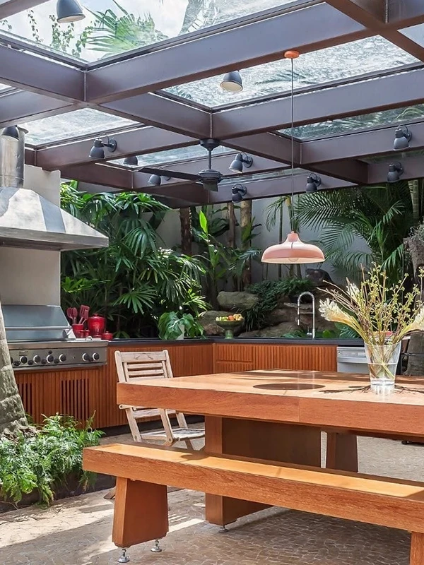 espaço ao ar livre com mesa e pergolado metálico com vidro
