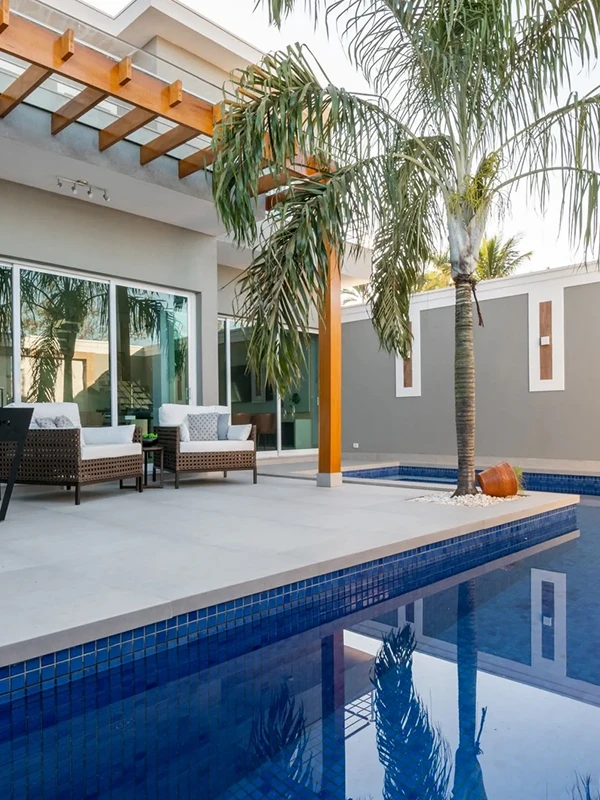 área de piscina com revestimento cimenticio e pergolado de madeira de canto