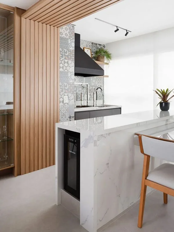 espaço para op café da manhã, com uma parede de painel ripado de mds e uma bancada de porcelanato branco com frigobar embutido