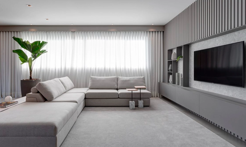 Uma sala de estar moderna com sofá cinza e TV.