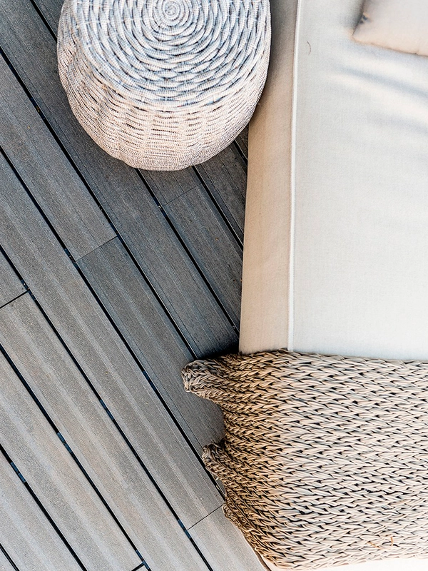 Uma cama num deck de madeira com um cesto de vime.