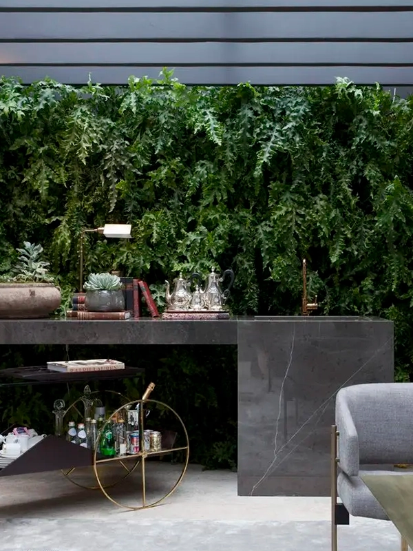 Uma sala de estar com mesa e cadeiras e uma parede com jardim vertical.