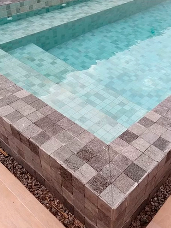 Piscina com borda de pedra hitam à sua volta.