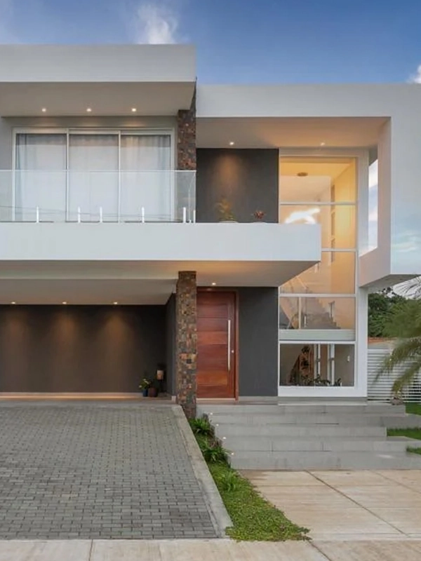 destacando a parede externa com cores neutrras e porta de madeira, com piso de concregrama na garagem