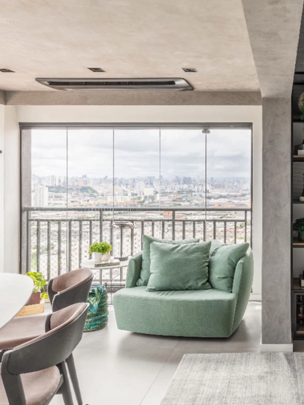 Uma sala com sofá verde e vista para a cidade.
