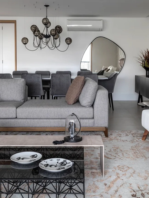 nuances da sala modrna com espelho e sofa cinza com almofadas coloridas para destaque 