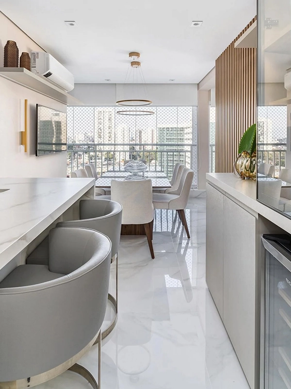 Porcelanato Extrafino: A Solução para Reformas Limpas +22 Projetos para Inspirar 51 Cozinha moderna e área de jantar com elegantes armários brancos, bancada em porcelanato extrafino, banquetas cinza e mesa de jantar rodeada por grandes janelas com vista para a cidade.
