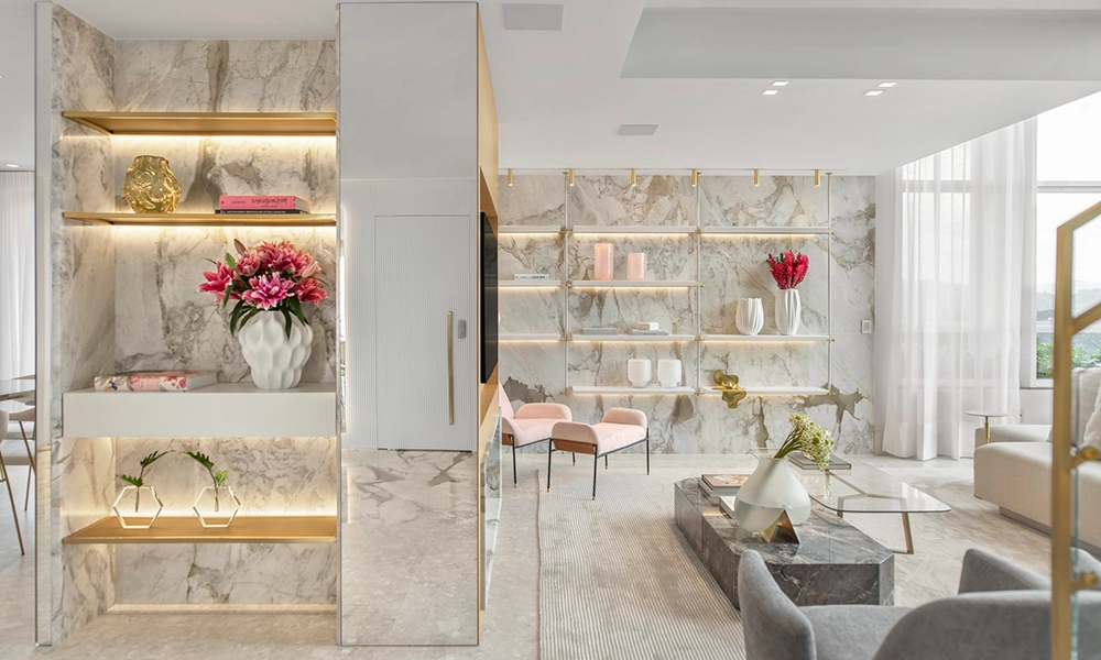 Sala de estar moderna com paredes de mármore, prateleiras embutidas, cadeiras rosa e mesa de centro de vidro.