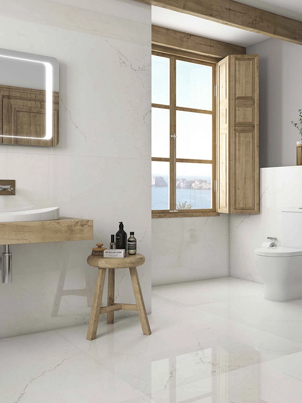 Interior moderno do banheiro com pia de madeira, banqueta com produtos de toalete, vaso sanitário de parede e revestimento branco com vista para o mar.