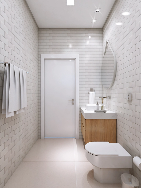 Interior moderno do banheiro com revestimento branco, penteadeira de madeira, espelho oval, vaso sanitário e toalhas penduradas em um rack ao lado de uma porta branca fechada.