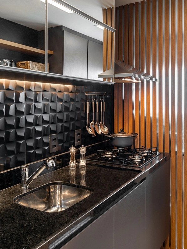 Cozinha moderna com backsplash preto texturizado (revestimento preto), detalhes em ripas de madeira, pia em inox e fogão a gás com utensílios suspensos.