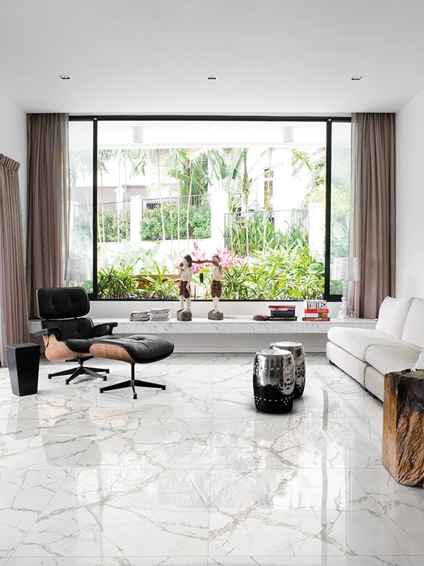 Sala de estar moderna com piso de mármore branco, grandes janelas com vista para o jardim, poltrona preta, sofá branco e detalhes decorativos.