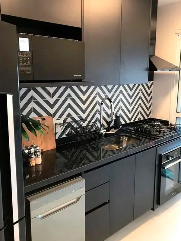 Cozinha moderna com armários pretos e cinza, backsplash em zigue-zague do Revestimento Preto e eletrodomésticos em inox, incluindo fogão a gás e forno.